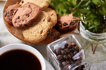 Side view of a plate of chocolate chip cookies on a white plate on homespun tablecloth, selective focus