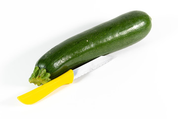 Frische Zucchini mit einem gelben Küchenmesser isoliert auf weißem Hintergrund