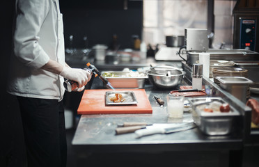 Restaurant Chef cook preparing salmon filet flambe.