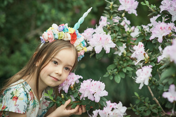 Fantasy little girl with rainbow unicorn horn with flowers in azalea park. for Halloween