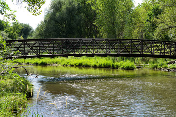 Summer Creek - A iron trail bridge over a full summer creek. Bear Creek, Denver-Lakewood, Colorado, USA. 