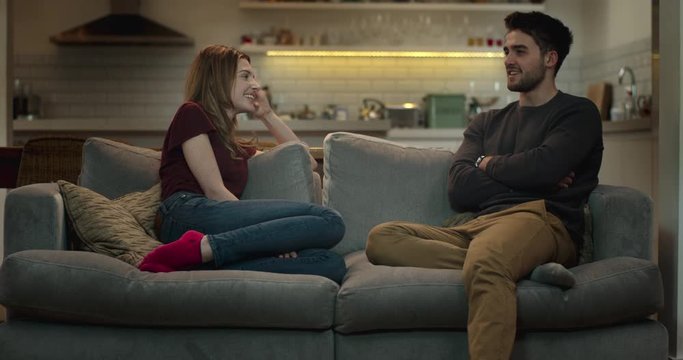 Man and woman sitting on a sofa in a cozy living room having a conversation.