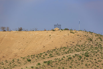 Chanukiah and flag on hill in desert under blue sky