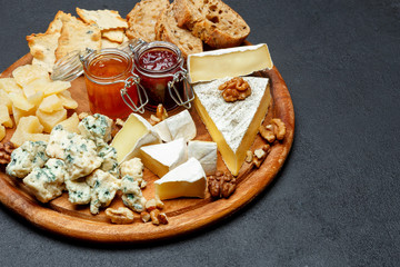 Brie cheese on a wooden Board with bread and sweet jam