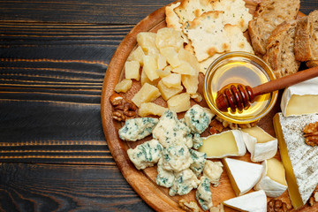 Brie cheese on a wooden Board with bread and sweet honey