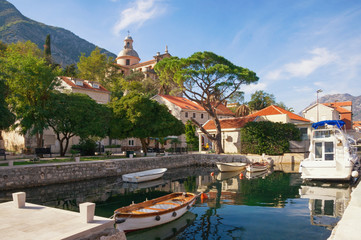 Fototapeta na wymiar Ancient Mediterranean town of Prcanj on sunny autumn day. Montenegro, Bay of Kotor, view of small harbor for fishing boats and Birth of Our Lady Church