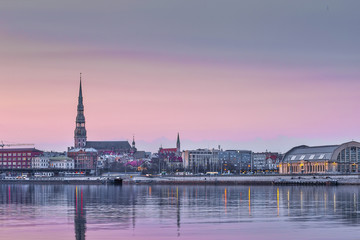 Night view on the illuminated riverside with reflection on the river in Riga