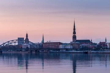 Obraz premium Night view on the illuminated riverside with reflection on the river in Riga