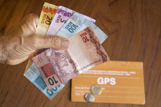 Pessoa segurando dinheiro brasileiro para previdência social
