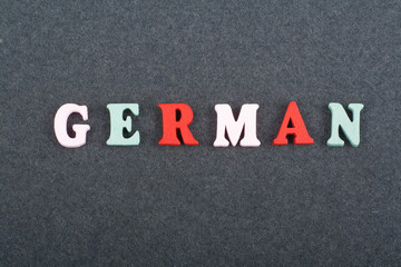 German word on black board background composed from colorful abc alphabet block wooden letters, copy space for ad text. Learning english concept.