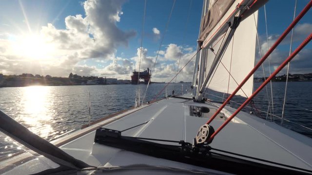 Closeup of the mast and sails of yacht while driving. POV shot. View from captain's cabin on bow. Magnificent seascape of Norway. Sea voyage, cruise. Bright shining sun, blue clear sky, boundless sea.
