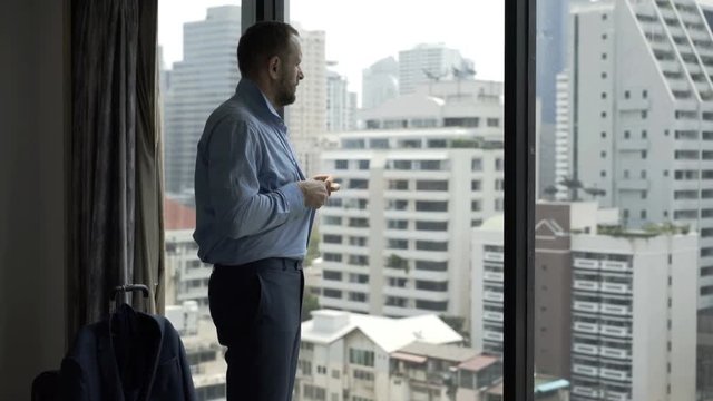 Businessman undo buttons in shirt and take it off in his apartment
