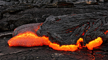 Hot magma escapes from an earth column as part of an active lava flow, the glowing lava slowly...