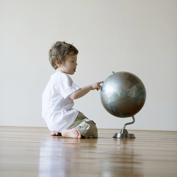 Boy looking at globe while sitting at home