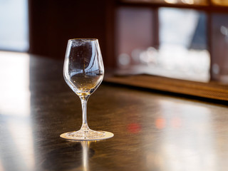 Close-up detail of an empty wine glass with smudged rims and multiple reflections on a coaster and wooden bar counter. Shallow depth of field. Kyoto, Japan. Travel and party concept.