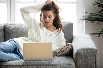 Shocked young woman looking at laptop computer screen at home unpleasantly surprised by email notification message reading bad news online about debt, unexpected rejection, having financial problem