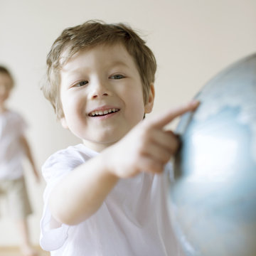 Smiling boy pointing on globe while sitting at home