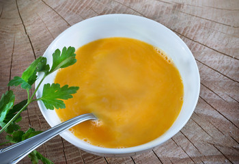 Carrot soup with cream and parsley on dark wooden background Top view