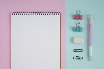 Concept for girl's desktop. On the desk is laptop, notepad for notes, phone,  pen, pencil, paper clips, eraser, office supplies, spring tree twigs. The background is turquoise with white. Flat lay.