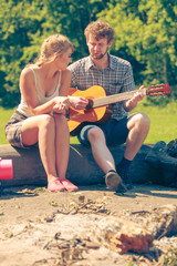 Young couple camping playing guitar outdoor