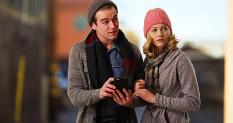 Fototapeta premium Friends in winter clothes taking a walk outdoors and using cell phone 