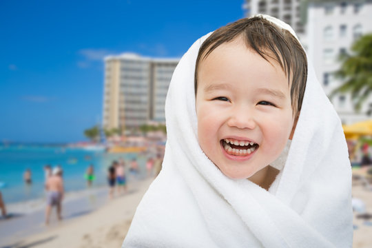 Happy Cute Mixed Race Chinese and Caucasian Boy On Waikiki Beach, Hawaii Wrapped In A Towel