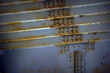 Bolts on a fragment of a massive girder bridge gray. Original background. Rust. Blue.