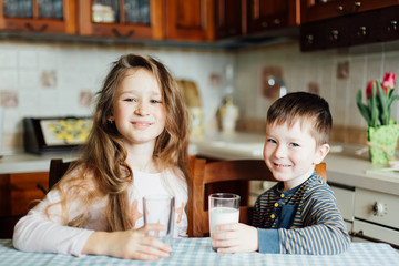 Children drink milk in the kitchen at the morning