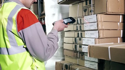 A warehouse worker uses a barcode scanner - Powered by Adobe