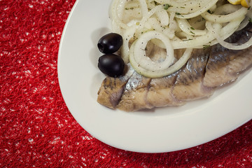 Sliced herring with onions and lemon on a plate