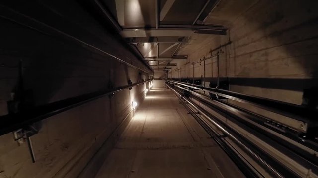 The cabin moves down in an elevator shaft. 02 The view is directed downwards. The camera is moving. The lights in the shaft give the ride its own rhythm.