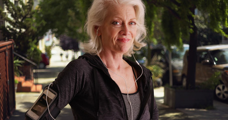 Confident woman in her 50s out jogging posing with confidence on sidewalk