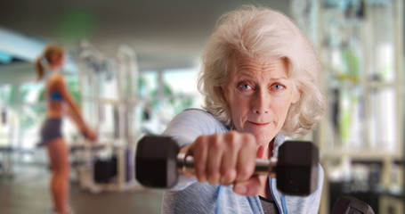 Fit elderly white lady at gym working out and looking at camera with determination