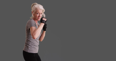 Athletic woman in her 50s posed in martial arts stance on gray backdrop