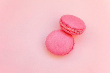 Top view of mini pink macaron or macaroon french desserts cake on soft sweet pink pastel paper flat lay background