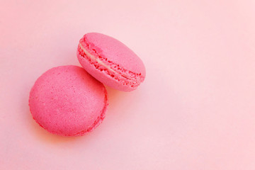 Top view of mini pink macaron or macaroon french desserts cake on soft sweet pink pastel paper flat lay background