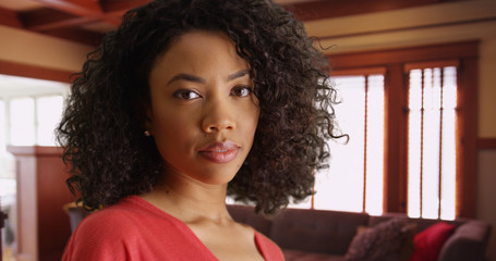 Gorgeous black millennial woman staring at camera in her living room