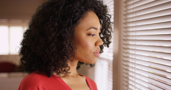 Black Millennial Young Lady Thinking While Looking Out Window Inside Home