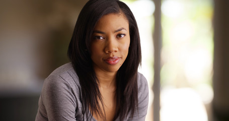 Portrait of beautiful African woman with straight hair looking at camera indoors