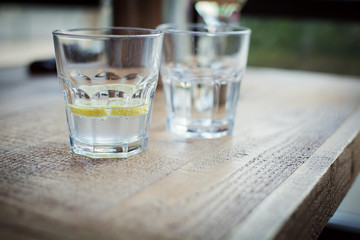 glass of clear clear water with a lemon on a wooden table