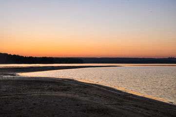 Fototapeta premium Tranquil nature scene. Sunset dawn sky above the sandy beach and water surface of the river Ob in soft evening colors. Altai, Russia.