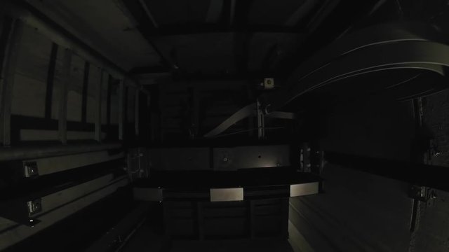 In a dark elevator shaft, the cabin moves up one floor and stops there.