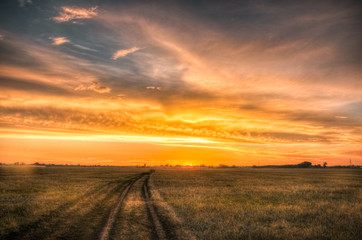Fototapeta na wymiar Road in the steppe under amazing cloudy sunset sky