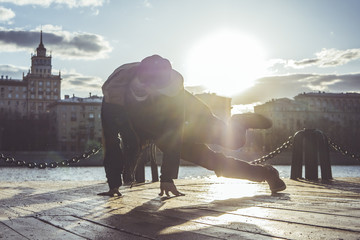 young man in snapback breakdancing in the city street during sunset - Powered by Adobe