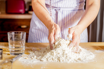 Making dough by female hands on wooden table