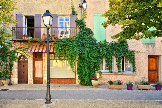 Fototapeta Traditional house fronts with wooden shuttered windows and leafy facade, Provence, France