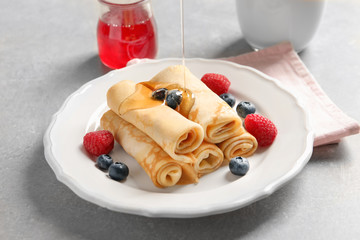 Pouring honey on thin pancakes with berries, closeup