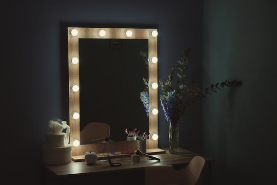 Table with beautiful mirror and cosmetics in modern makeup room