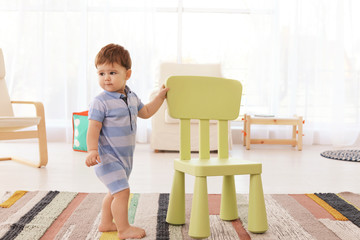 Cute baby with chair at home. Learning to walk