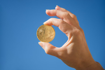 Fototapeta na wymiar Hand holding golden bitcoin coin on blue sky background
